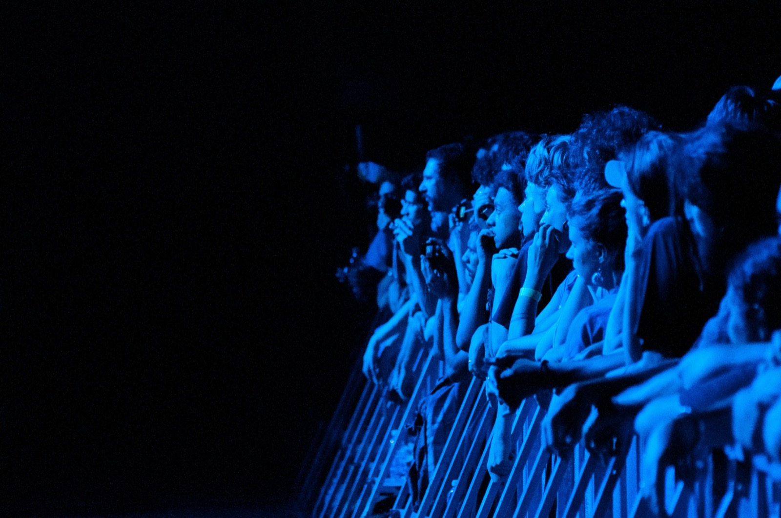 A crowd of fans at a concert lit in cool blue stage light